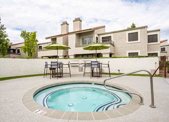 Apartment Scottsdale, AZ - The Sycamore at Scottsdale - An exterior view the spa featuring lounge seating, umbrellas, and grills