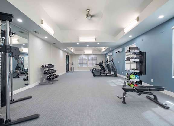 A spacious gym with a variety of equipment including treadmills, stationary bikes, and weight machines.