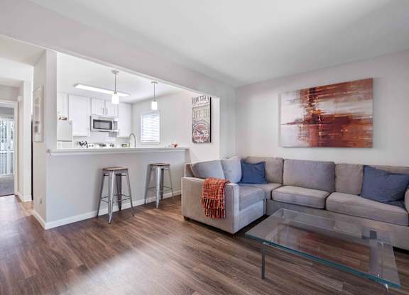 A modern living room with a grey couch and a glass coffee table.