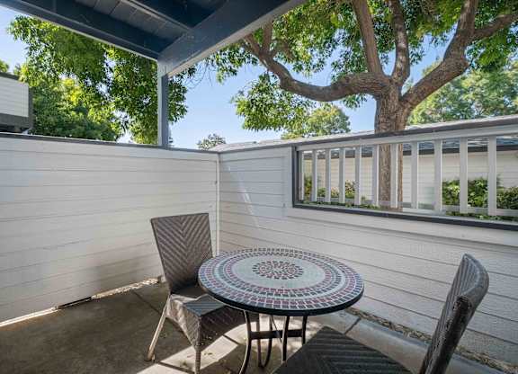 A patio with a table and chairs under a tree.