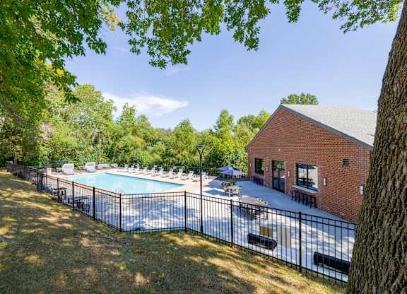 A pool surrounded by a black fence with a building in the background.