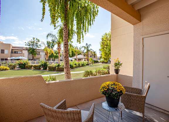 Apartments in South Phoenix - Village at Lakewood - Patio with View of Apartment Complex, Outdoor Furniture, and Potted Flowers