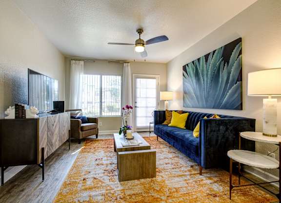 Dog-Friendly Apartments in Phoenix AZ - Village at Lakewood - Living Room with Wood-Style Flooring, Ceiling Fan, and Large Window