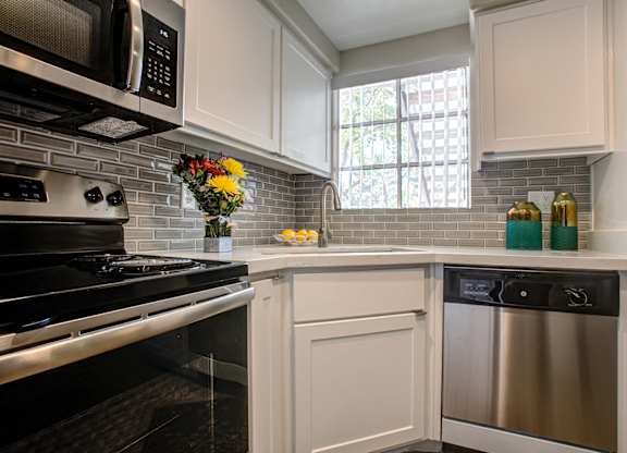 Luxury Apartments in Phoenix AZ - Village at Lakewood - Modern Kitchen with Tiled Backsplash, White Cabinetry, and Stainless-Steel Appliances