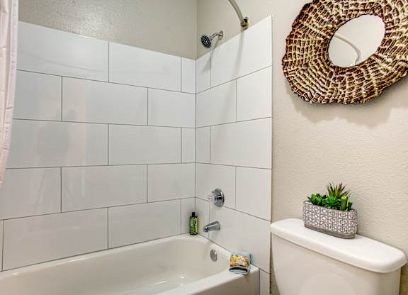 Apartments for Rent in South Phoenix - Village at Lakewood - Bathroom with Bathtub, Circle Mirror, and White Tiles