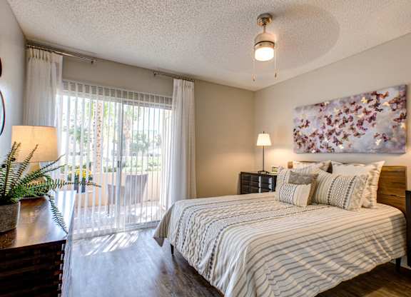 Pet-Friendly Apartments in Phoenix AZ - Village at Lakewood - Bedroom with Wood-Style Flooring and Access to Patio