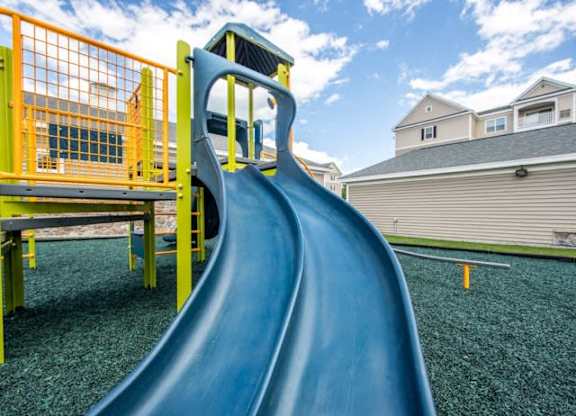 a slide in a playground with houses in the background