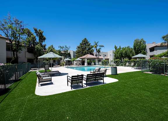 1-Bedroom Apartments in Ahwatukee, Phoenix, AZ - Village at Lakewood - Pool Area with Artifical Turf, Pool, Sundeck with Lounge Seats and Umbrellas.