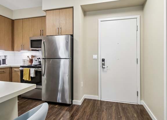 A kitchen with a refrigerator, microwave, and oven.