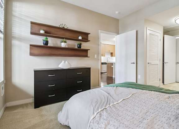 A bedroom with a large bed, a dresser, and a mirror.