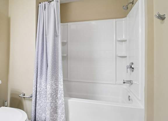 A white bathtub with a grey shower curtain in a bathroom.