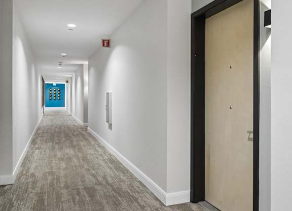 A long hallway with a blue door at the end.
