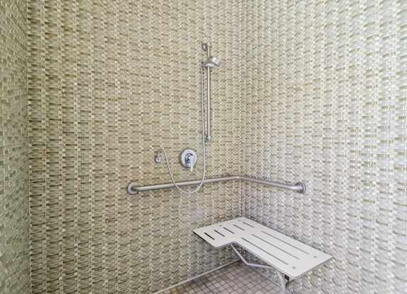 A shower with a bench and a shower head.