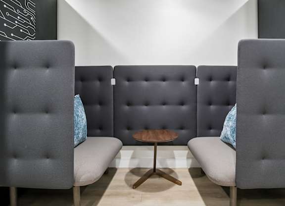 Three grey chairs with blue pillows are arranged in a row.