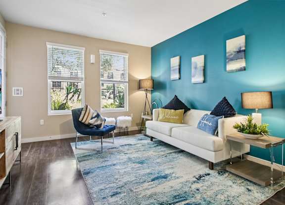 A living room with a blue accent wall and a white couch.