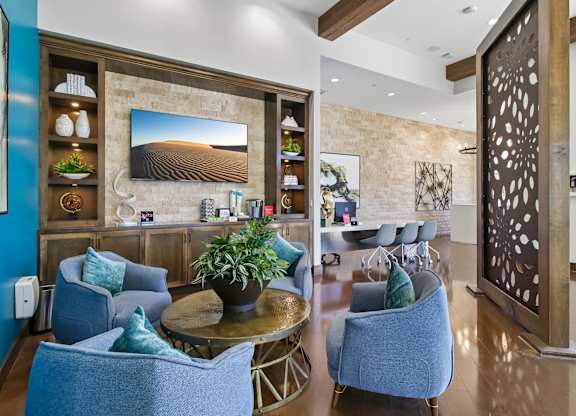 A living room with blue chairs and a wooden table.