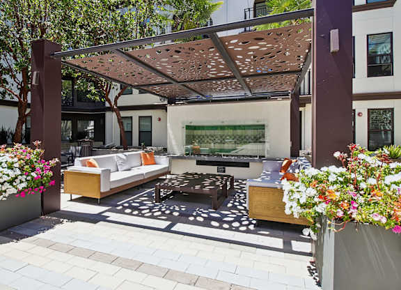A patio with a white couch and a table under a pergola.