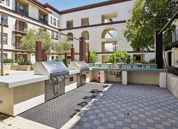 A patio with a grill and a table with chairs.