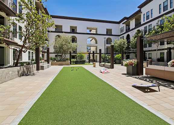 A courtyard with a green lawn and a building in the background.