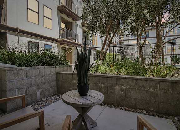 A small table with a vase on it sits in the middle of a patio.