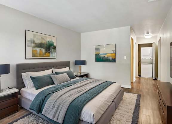 A bedroom with a large bed and a painting on the wall.