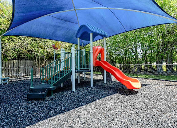 Apartments In Coconut Creek for Rent – Waterview at Coconut Creek – playground with a slide and a swing set under a blue umbrella
