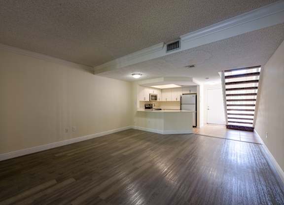 Pet-Friendly Apartments in Coconut Creek, FL – Waterview at Coconut Creek – empty living room with wood floors and a kitchen