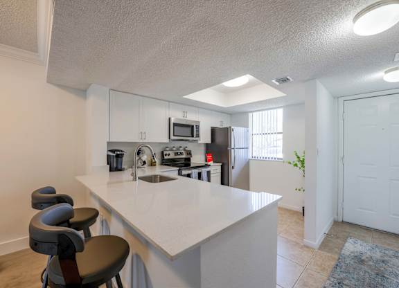 Pet-Friendly Apartments in Coconut Creek, FL – Waterview at Coconut Creek – kitchen with an island and stools in front of a kitchen counter top