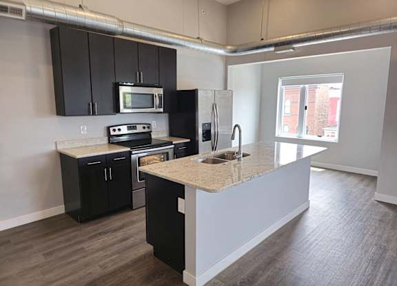 A kitchen with black cabinets and a granite countertop.