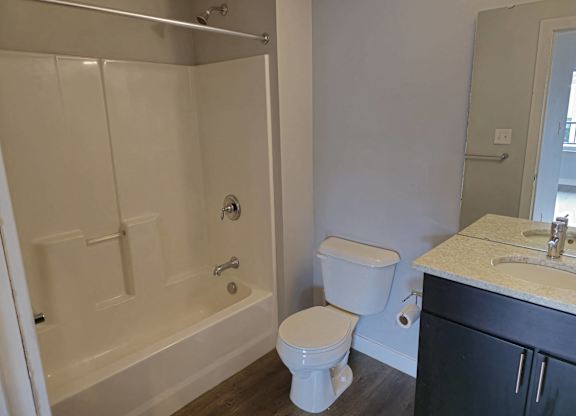A white toilet sits next to a white bathtub in a bathroom.