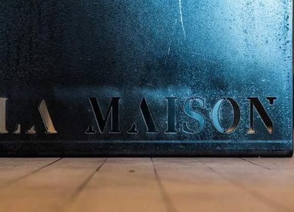 A blue sign with the word "LA MAISON" on it.