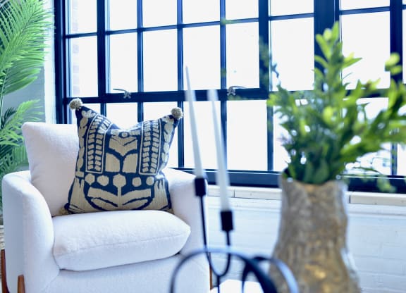 a white chair with a pillow in front of a window