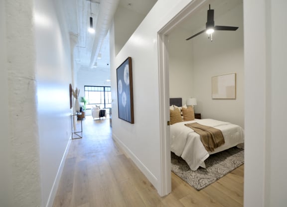 a bedroom with a bed and a hallway to a living room