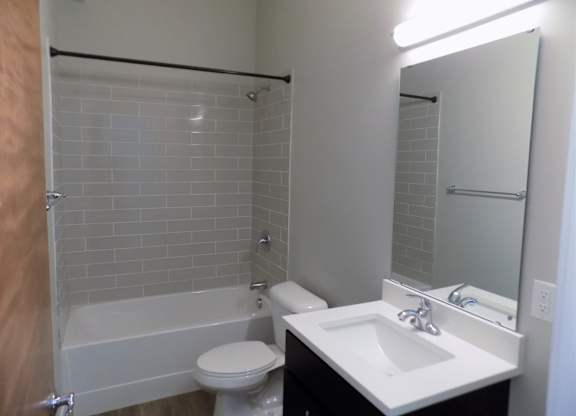 A white sink is on a countertop next to a white toilet in a bathroom.