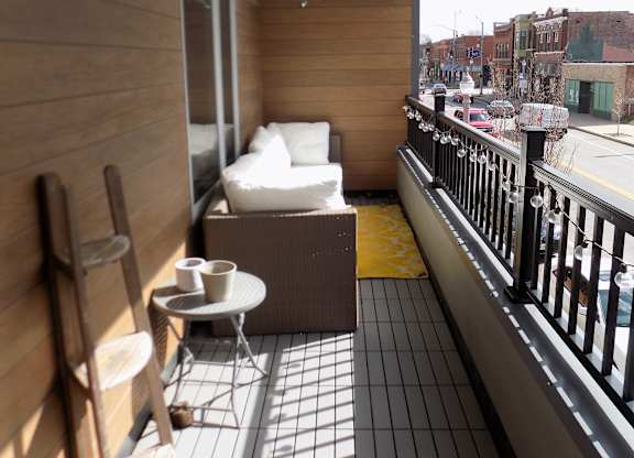 A balcony with a chair, table, and a bag of chips.