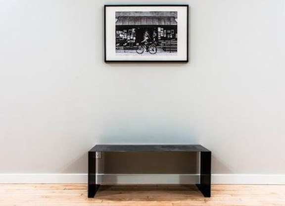 A black and white picture of a bicycle is hanging on a wall above a black coffee table.