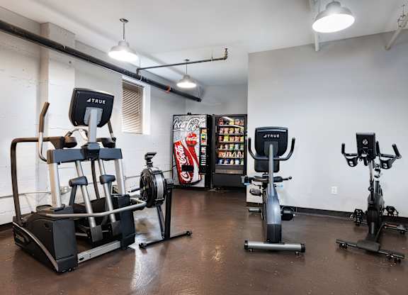 A gym with a variety of equipment including a rowing machine, a stationary bike, and a treadmill.