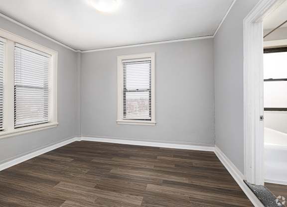 A room with wooden flooring and a window with blinds.