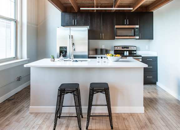 A kitchen with a white island and black stools.