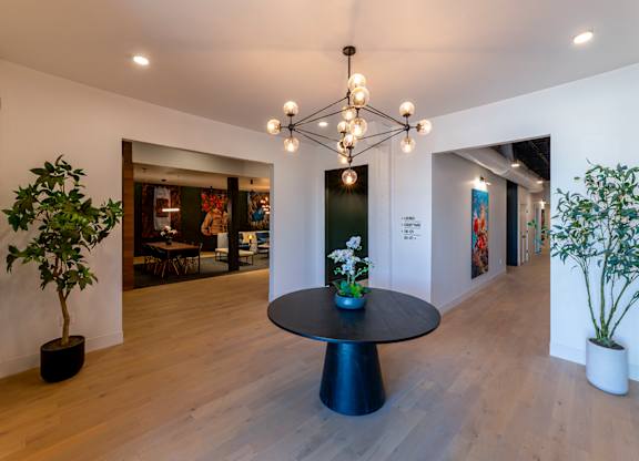 A room with a round table and a plant on the side.