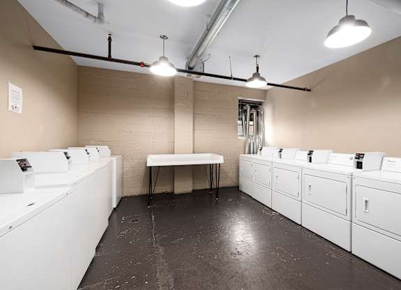 A room with white washing machines and a table.