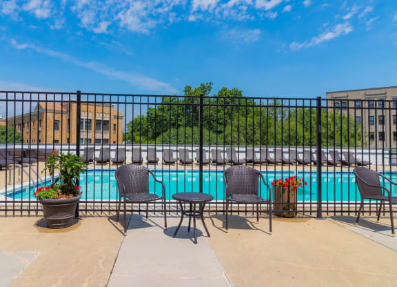 a swimming pool with tables and chairs next to a fence at The Argonne Apartments, Washington