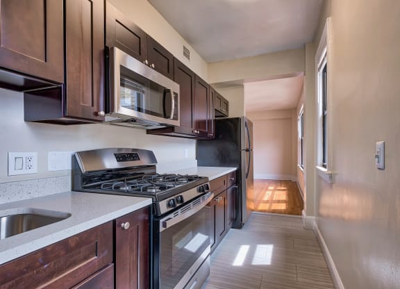 an empty kitchen with wood cabinets and stainless steel appliances at The Argonne Apartments, Washington, 20009