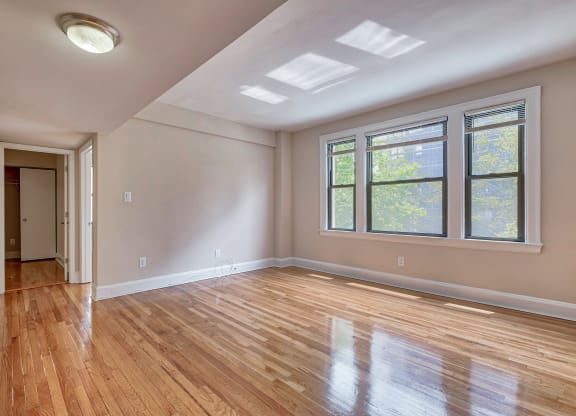 an empty living room with hardwood floors and a large window at The Argonne Apartments, Washington DC