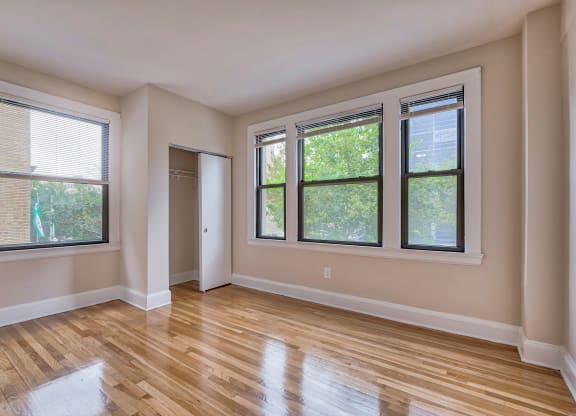 an empty living room with wood floors and windows at The Argonne Apartments, Washington, DC