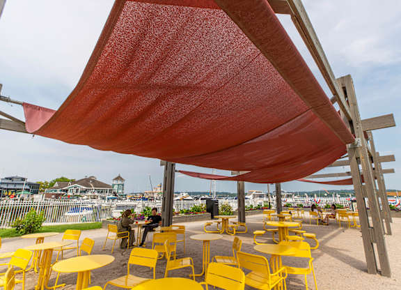 A red canopy over yellow chairs and tables.
