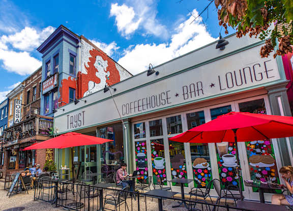 A bar and lounge with people sitting at tables under red umbrellas.