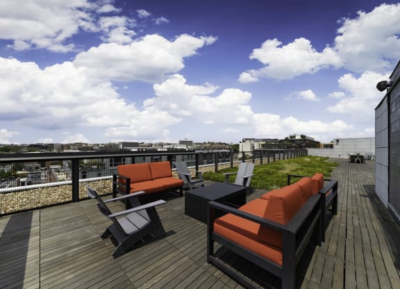 a rooftop deck with orange and black furniture and a blue sky with white clouds at The Shay, District of Columbia