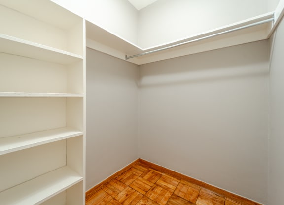 a walk in closet in a home with gray walls and a wooden floor