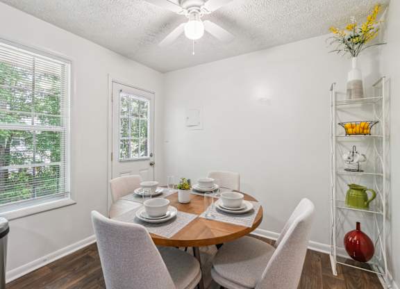 A dining room with a table set for two and a window with blinds.